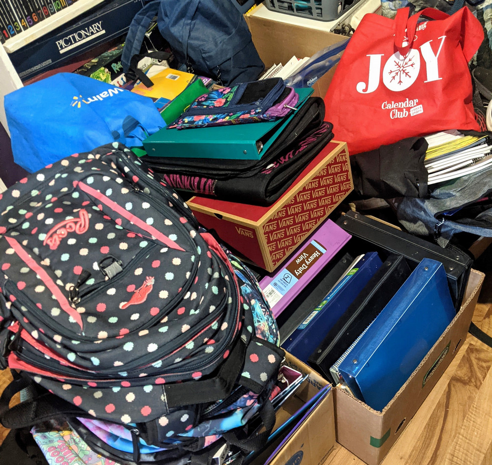 a pile of backpacks, binders, notebooks, shoes and more