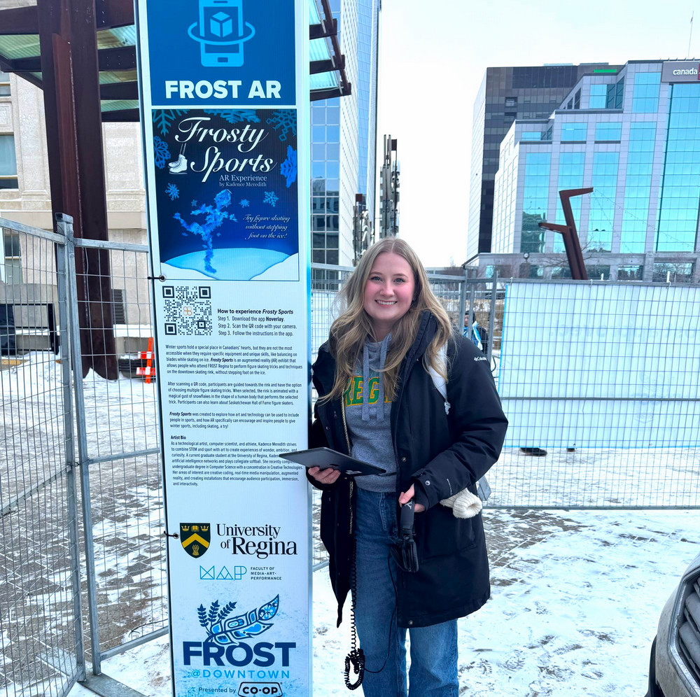 a smiling person standing beside a sign