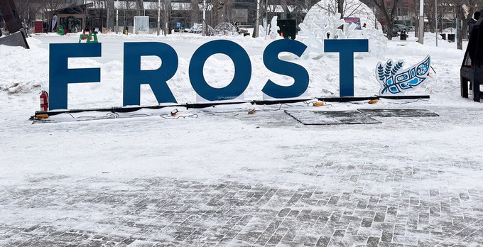 A large FROST sign in a snowy downtown park