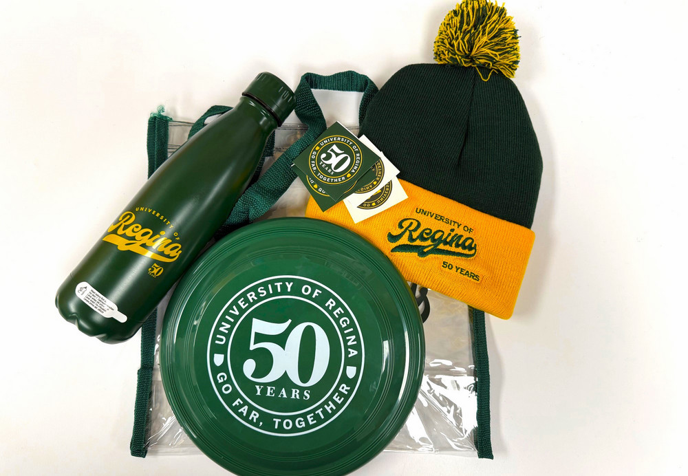 Collection of U of R themed items displayed on a table – water bottle, toque, frisbee, tote, stickers, and temporary tattoos.