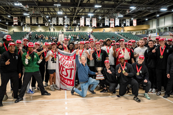 The U of R Rams pose with a banner in a gym