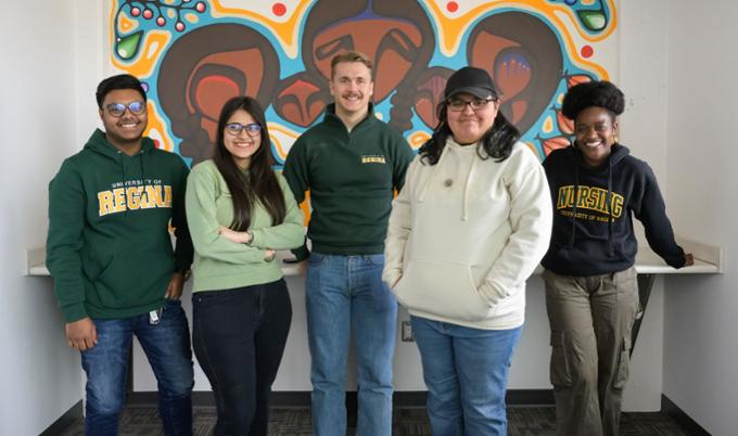 Five students in front of mural