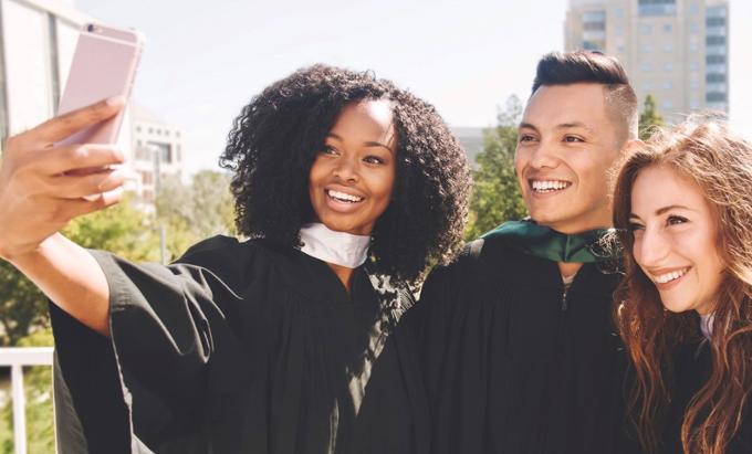 Three students taking a selfie in convocation gowns.