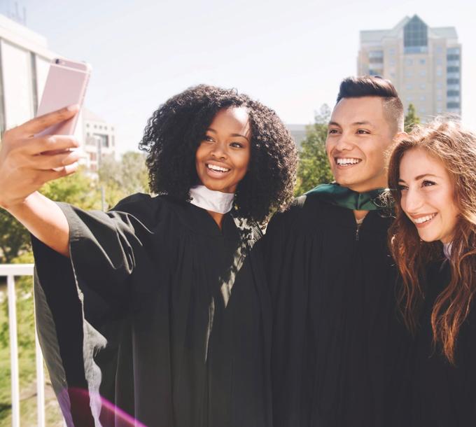 Three students in convocation robes smiling