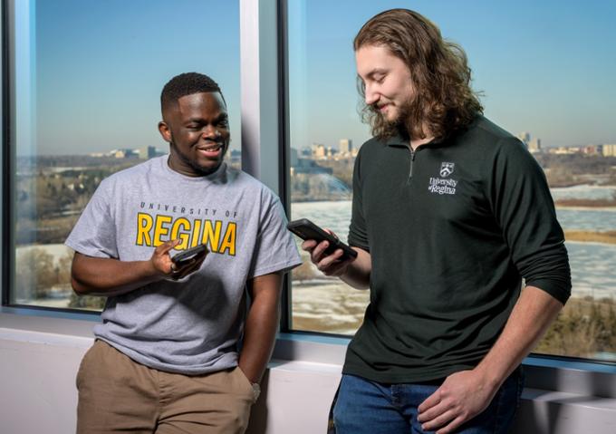 Two students talking looking at phone.