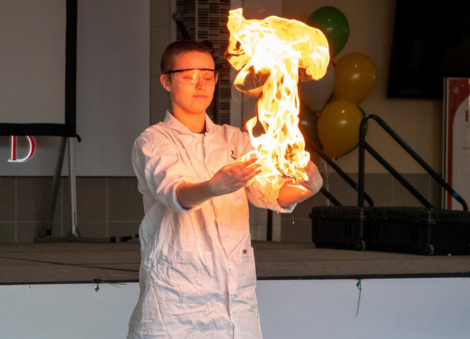 A person in a lab coat holding some flaming material