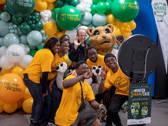 Six students take a group selfie with President Keshen and a mascot